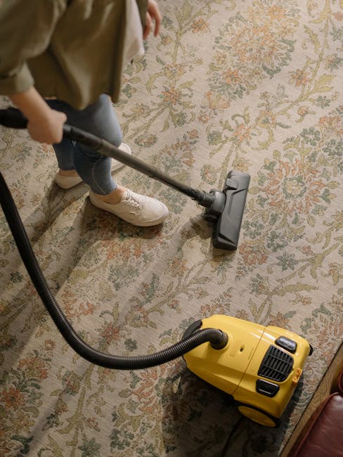 A team of three professional cleaners from East Dulwich Carpet Cleaners performing surface cleaning and deep cleaning in a modern living room. The room features a tiled floor being vacuumed and mopped